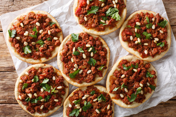Beef Sfiha Lebanese mini pizzas topped with ground beef, onions, tomato, and pine nuts closeup. Horizontal top view