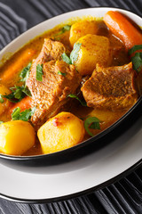 Potjiekos South African lamb stew with vegetables close-up on the table. vertical