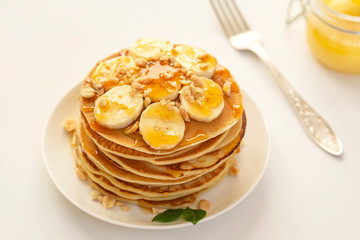 Sweet Homemade Stack of Pancakes with banana, nuts and honey. Delicious breakfast.