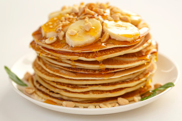 Sweet Homemade Stack of Pancakes with banana, nuts and honey. Delicious breakfast.