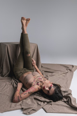 Young brunette cute slim model in skinny jeans raising her legs up