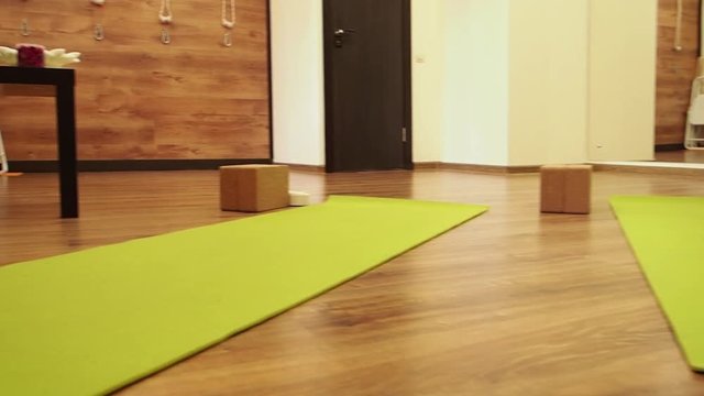 Empty white space in fitness center, a wooden panel walls, natural wooden floor, modern loft studio, unrolled yoga mat on the floor, comfortable open area for sport and exercises. Slow Motion