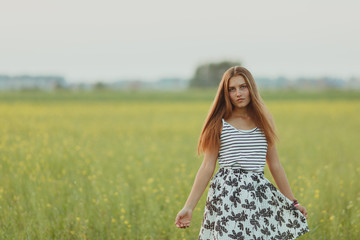 Portrait of a beautiful girl in a field with yellow flowers, summer, sunset