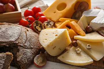Assortment of tasty cheese with bread on wooden table