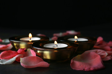 Burning candles with flower petals for celebration of Divaly on dark background