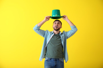 Handsome young man with green hat on color background. St. Patrick's Day celebration