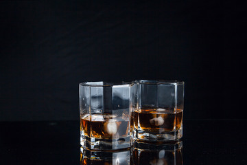 Two glasses of whiskey with ice isolated on black background..