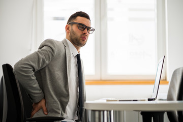 Young businessman is having pain in his back.