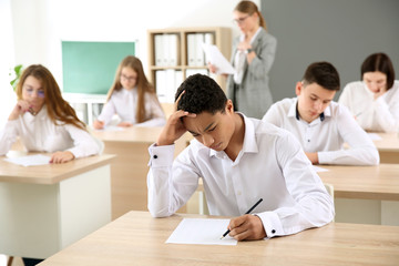 Fototapeta na wymiar Pupils passing school test in classroom