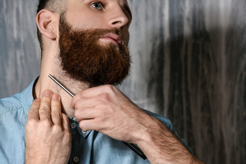 Bearded man shaving on grey background