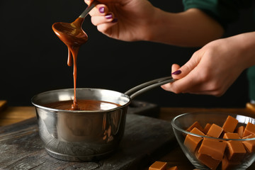 Woman cooking liquid caramel in kitchen