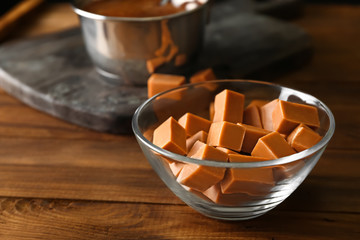Glass bowl with caramel candies on table