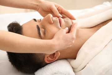 Fototapeta na wymiar Man receiving face massage in beauty salon