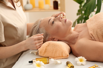 Obraz na płótnie Canvas Mature woman undergoing treatment with face serum in beauty salon