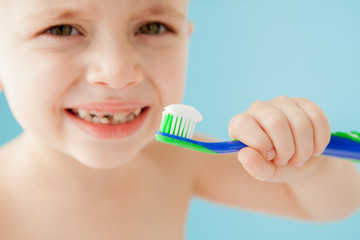 Portrait of little boy with toothbrush on blue background