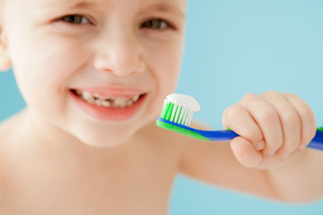 Portrait of little boy with toothbrush on blue background