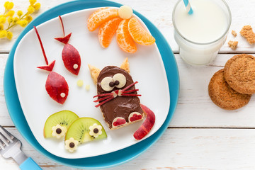 Fun Food for Kids - cute funny cat shaped toast covered with chocolate spread and decorated with fish shaped apple pieces, kiwi slices and tangerines