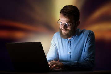 Young handsome businessman working late at night in the office with warm lights in the background
