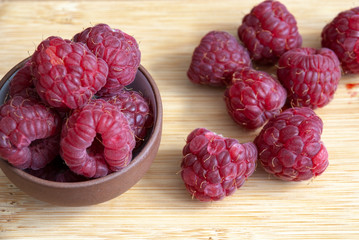 Close-up of raspberries in ceramic bowl on wooden board