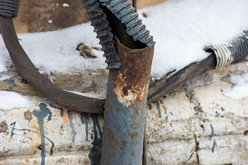 Rusty damaged pipe and a corrugated hose with an electrical cable covered snow