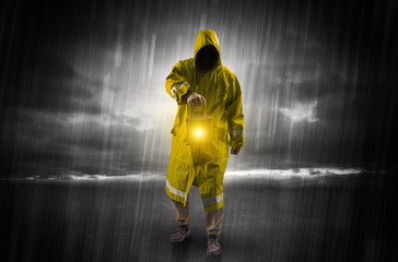 Raincoated man walking in storm with glowing lantern in his hand
