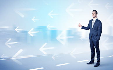 Young businessman hitchhiking near the city with arrows around concept