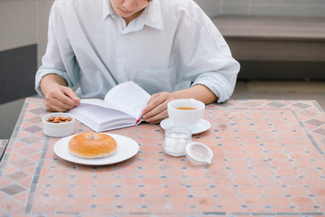Obraz na płótnie Canvas Portrait of a handsome man reading a book and enjoying his coffee.