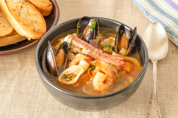 Homemade cioppino in a bowl and toast - Italian-American seafood soup - fish, mussels, shrimps and squids.