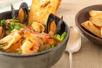 Homemade cioppino in a bowl and toast - Italian-American seafood soup - fish, mussels, shrimps and...