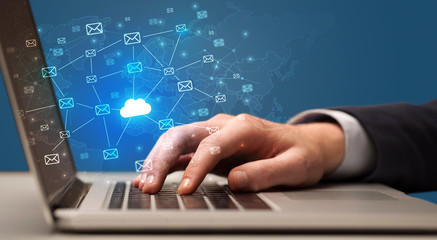 Businessman hand sending a bunch of messages on laptop with cloud computing concept

