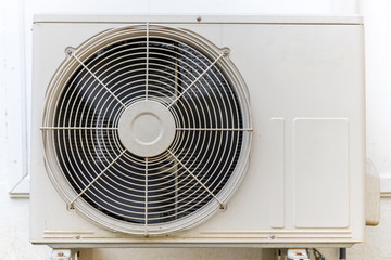 Condenser air conditioner compressor unit on concrete wall.