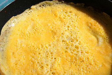 Delicious yellow beaten egg fried in pan omelette scramble egg close up with hole of air on the surface Asian cuisine traditional food . 