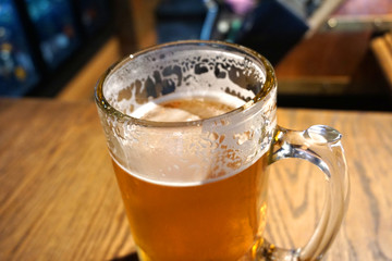 Delicious beautiful ice cold ice tube jar of beer glass on wooden table in vintage bar top view close up brew beer with white foam fresh beverage on summer time alcohol party 