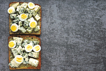 Keto toasts with blue cheese and quail eggs. Healthy wheat rye toasts with cheese and egg.