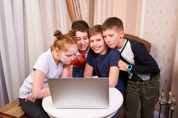 Group of childrens with laptop, boys and girl sitting at the table with laptop , smiling and looking at laptop