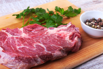 Raw beef steak with spices Leaves of coriander on wooden cutting board. Ready for cooking.