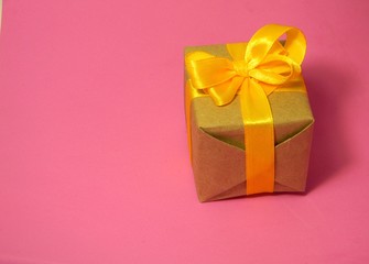 Small present box on a pink background. Kraft paper. Suitable for International Womens Day
