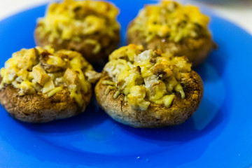 Grilled mushrooms stuffed with cheese on blue plate