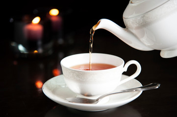 Pour tea in the cup with candle light.
