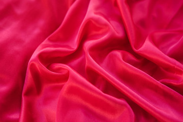 Close up red fabric. The purple fabric is laid out waves. Pink sateen fabric for background or texture.