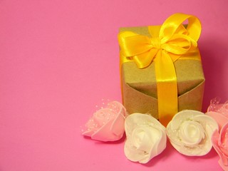Small present box on a pink background. Kraft paper. Suitable for International Womens Day. 8 march