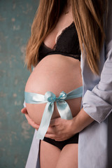 babybauch mit blaumen schleifenband