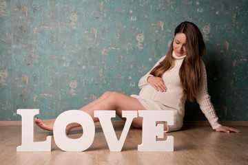 schwangere frau sitzt vor love buchstaben
