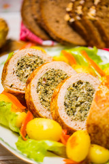 Meatloaf with spinach stuffing served with fried potatoes and carrot.