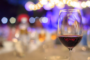 Glass of Red Wine on the food table with Lights Bokeh at night background.