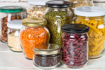 Cereals, Legumes, and beans in glass jars on white kitchen table. 