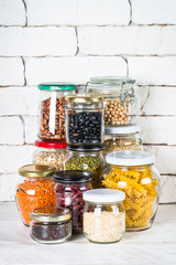 Cereals, Legumes, and beans in glass jars on white kitchen table. 