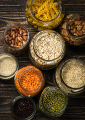 Cereals, Legumes, and beans in glass jars on  dark wooden table. 