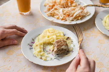 mashed potatoes with meat cutlet, steak on a plate, fork in hand