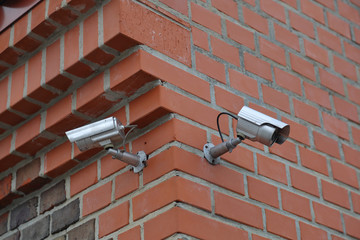 Outdoor silver security camera on a brick wall